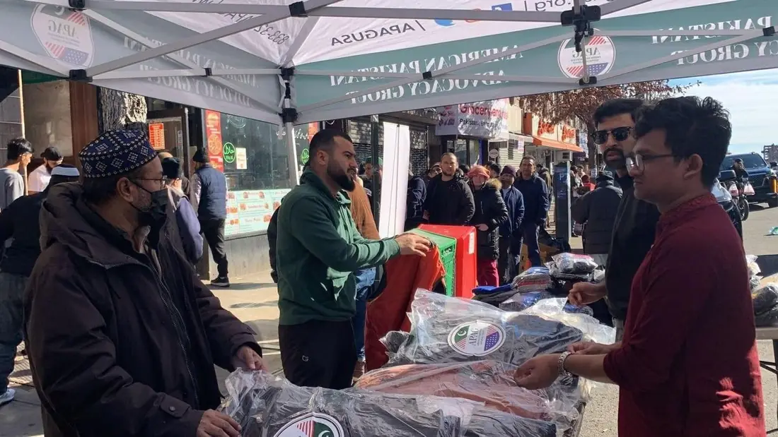 APAG Cares volunteer handing packaged winter clothing to a community member